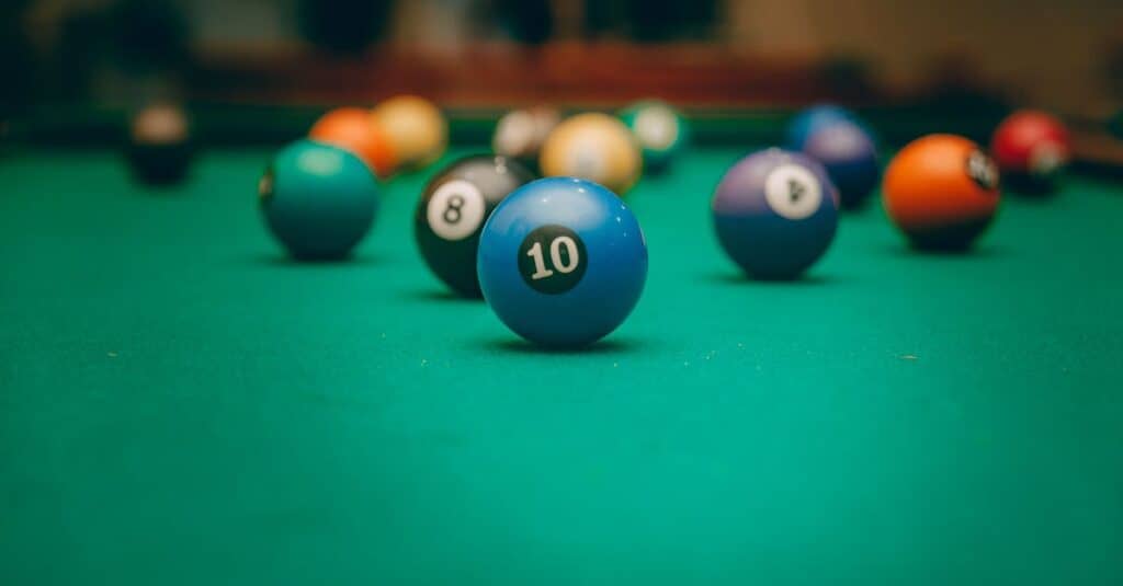 Close-up of a blue number 10 billiard ball on a pool table, with other colored balls scattered in the background.